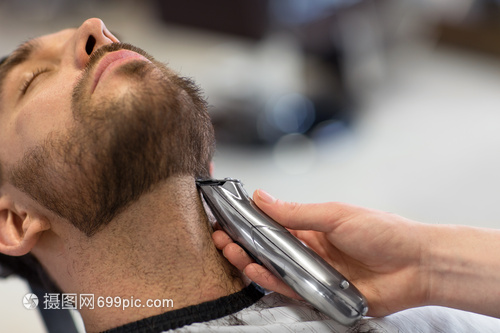 美容人的男人理发师与修剪剃须刀切割胡须理发店男人理发师沙龙剪胡子